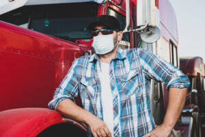 CDL truck driver standing in front of a truck wearing a mask